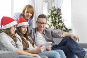 Family of four using digital tablet at home during Christmas